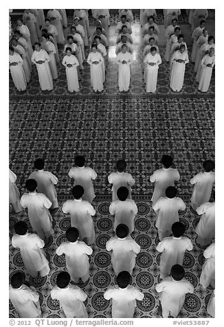 Men and women dressed in white stand in opposing rows in Cao Dai temple. Tay Ninh, Vietnam