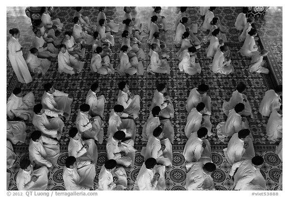 Worshippers dressed in white pray in neat rows in Cao Dai temple. Tay Ninh, Vietnam (black and white)