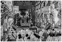 Dignitaries (in colored robes) and other followers praying at the Main hall, Cao Dai temple. Tay Ninh, Vietnam (black and white)