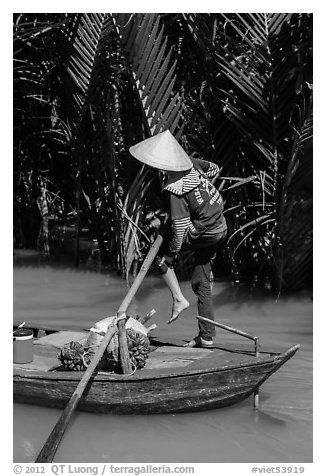 Woman standing in canoe on jungle canal, Phoenix Island. My Tho, Vietnam (black and white)