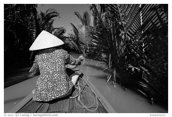 Woman rowing boat in canal lined up with vegetation, Phoenix Island. My Tho, Vietnam