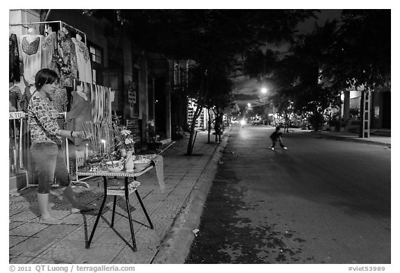 Woman tends to altar on street at dusk. Hoi An, Vietnam