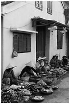 Vegetable vendors sitting in front of old house. Hoi An, Vietnam ( black and white)