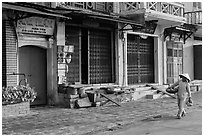 Woman carrying fruit in front of old storefronts. Hoi An, Vietnam ( black and white)