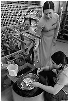 Workers demonstrate silkworm processing. Hoi An, Vietnam (black and white)