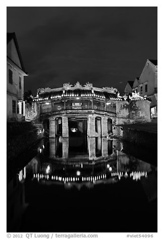 Illuminated Japanese covered bridge reflected in canal. Hoi An, Vietnam