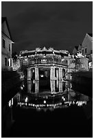 Illuminated Japanese covered bridge reflected in canal. Hoi An, Vietnam (black and white)