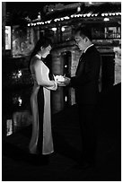 Couple holding candles in front of Japanese bridge at night. Hoi An, Vietnam ( black and white)