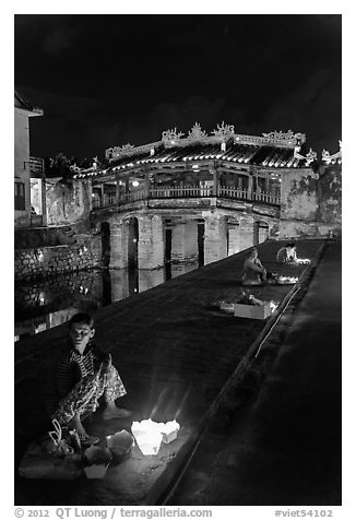 Candle vendors in front of Japanese bridge at night. Hoi An, Vietnam