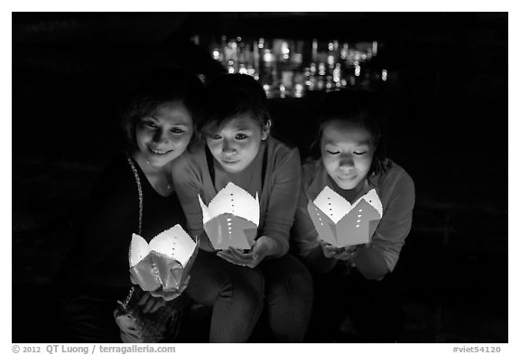 Faces of three women in the glow of candle boxes. Hoi An, Vietnam (black and white)