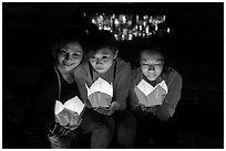 Faces of three women in the glow of candle boxes. Hoi An, Vietnam (black and white)