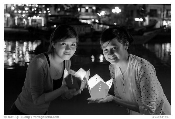 Two women lighted by candle box at night. Hoi An, Vietnam (black and white)