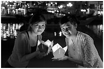 Two women lighted by candle box at night. Hoi An, Vietnam (black and white)