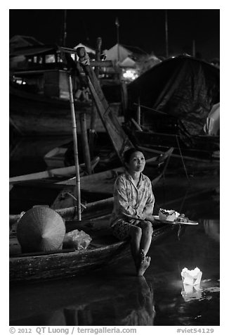 Woman sitting in boat with floating candles by night. Hoi An, Vietnam