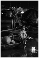 Woman sitting in boat with floating candles by night. Hoi An, Vietnam (black and white)
