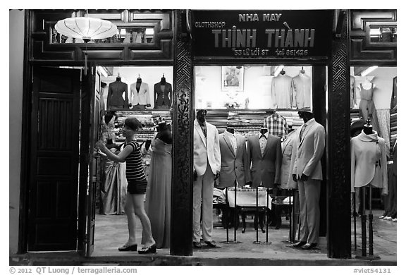 Woman closing doors of taylor shop. Hoi An, Vietnam (black and white)