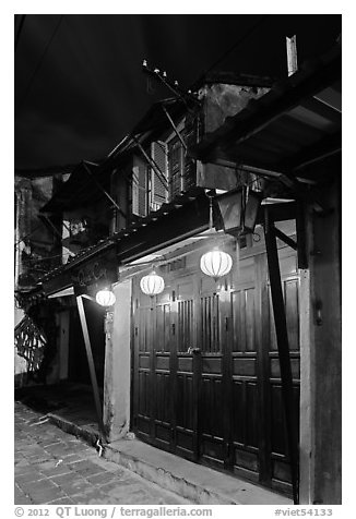 Townhouse with wooden doors lighted by paper lanterns. Hoi An, Vietnam