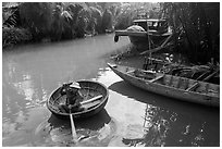 Man rows coracle boat in river channel. Hoi An, Vietnam ( black and white)
