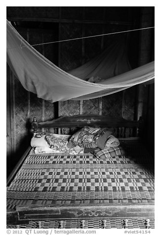 Wooden bed with straw mat and mosquito net, Cam Kim Village. Hoi An, Vietnam (black and white)
