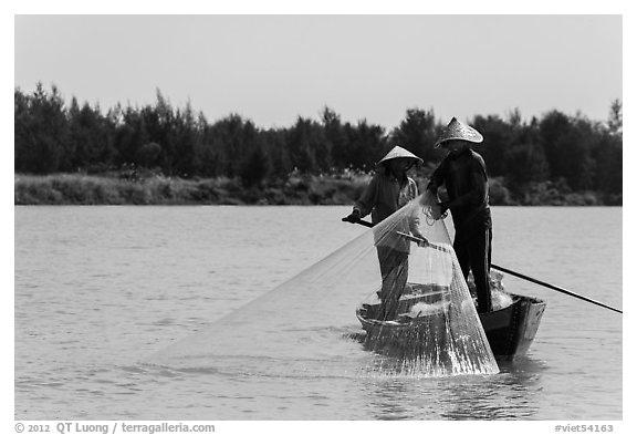 Fishermen standing in boat retrieving net, Thu Bon River. Hoi An, Vietnam