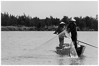Fishermen standing in boat retrieving net, Thu Bon River. Hoi An, Vietnam ( black and white)
