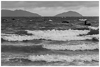 Man rowing coracle boat in distance amidst large waves. Da Nang, Vietnam (black and white)