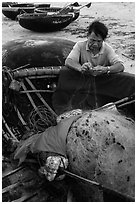 Fisherman repairing net on beach. Da Nang, Vietnam ( black and white)