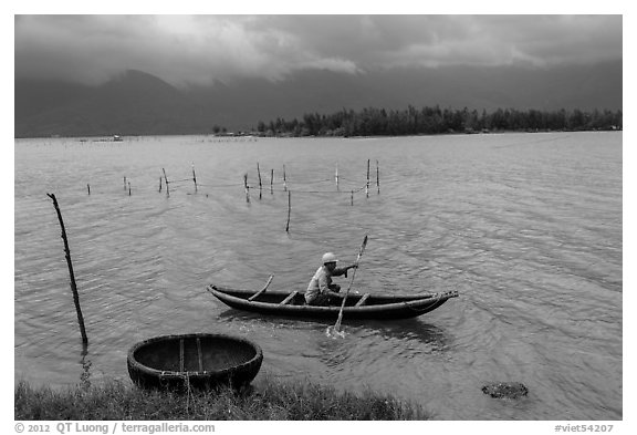 Fisherman rowing canoe in lagoon. Vietnam