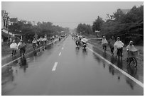 Riders wearing colorful ponchos on wet road on Hwy 1 south of Hue. Vietnam (black and white)