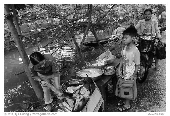 Boy waiting for donut coooked near canal, Thanh Toan. Hue, Vietnam (black and white)