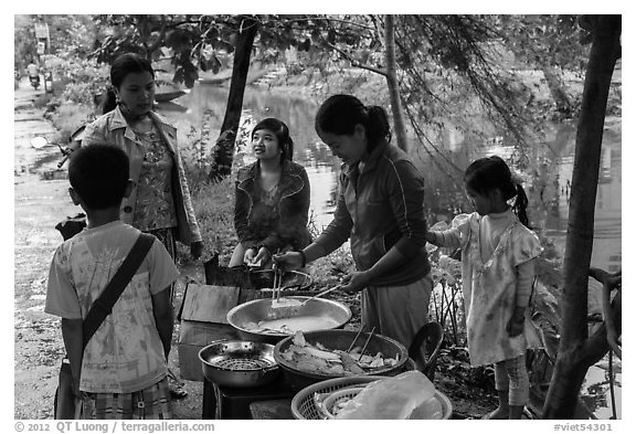 Woman preparing donuts near canal. Hue, Vietnam