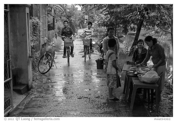 Canalside street with bicyclists and food stand, Thanh Toan. Hue, Vietnam (black and white)