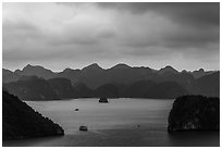 Boat amongst islands under dark sky. Halong Bay, Vietnam (black and white)