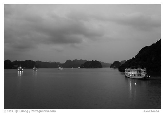 View of bay with lights of anchored tour boats at dawn. Halong Bay, Vietnam