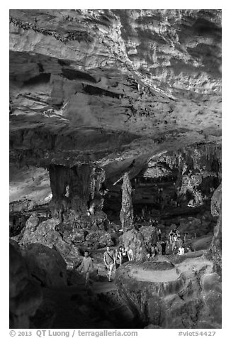 Tourists walking in cavernous chamber, Sungsot cave. Halong Bay, Vietnam (black and white)