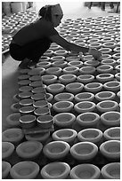 Woman laying ceramic bowls to dry in workshop. Bat Trang, Vietnam (black and white)
