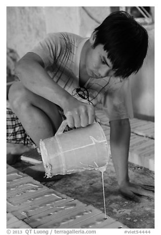 Man pouring clay into molds in ceramic workshop. Bat Trang, Vietnam (black and white)