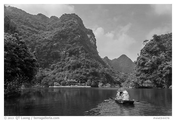 Boat journeying below tall lush cliffs, Trang An. Ninh Binh,  Vietnam (black and white)