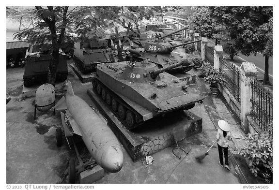 Woman sweeping floor in front of tanks, military museum. Hanoi, Vietnam