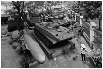 Woman sweeping floor in front of tanks, military museum. Hanoi, Vietnam ( black and white)