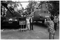 Tourists pose with tanks and helicopters, War Remnants Museum, district 3. Ho Chi Minh City, Vietnam (black and white)