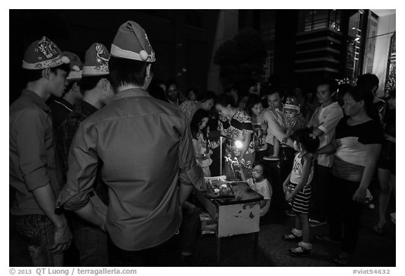 People gather around street hawker on Christmas eve. Ho Chi Minh City, Vietnam