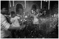 Revellers celebrating with spray in front of Notre Dame Cathedral on Christmas Eve. Ho Chi Minh City, Vietnam (black and white)