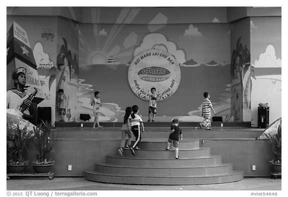 Children on stage next to militaristic mural, Dam Sen Water Park, district 11. Ho Chi Minh City, Vietnam