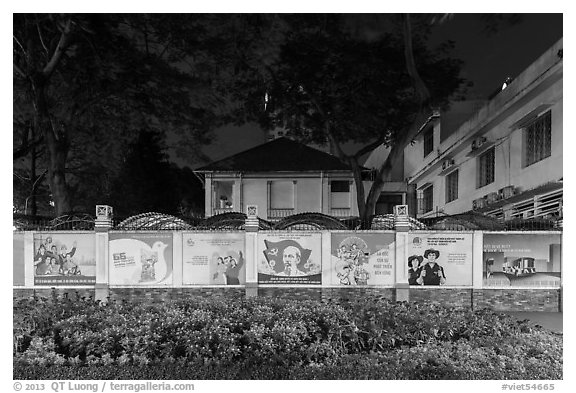 Fenced buildings with propaganda posters at night. Ho Chi Minh City, Vietnam (black and white)