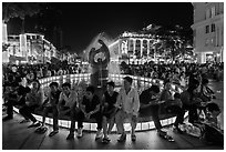 People sitting on fountain at night, New Year eve. Ho Chi Minh City, Vietnam (black and white)