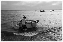 Man holding coracle boat. Mui Ne, Vietnam (black and white)