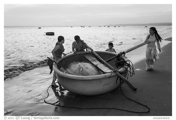 Family around their coracle boat. Mui Ne, Vietnam (black and white)