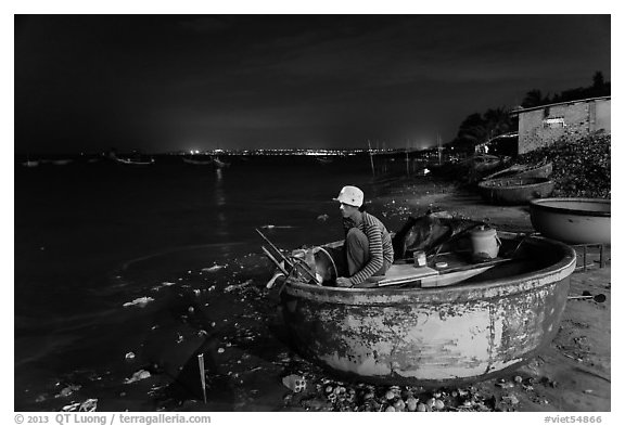 Man working on coracle boat at night. Mui Ne, Vietnam