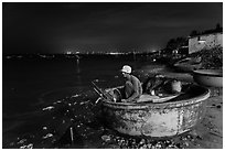 Man working on coracle boat at night. Mui Ne, Vietnam (black and white)